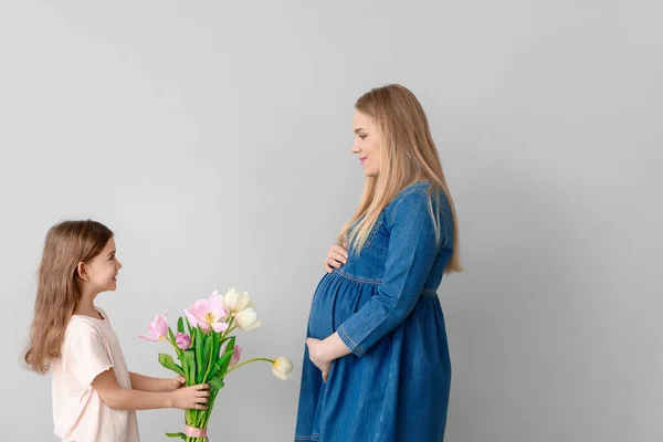 Menina Cumprimentando Sua Mãe Grávida Com Flores Fundo Claro — Fotografia de Stock