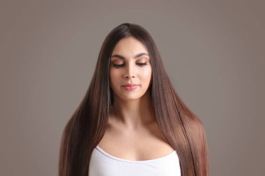 Gri arka planda güzel düz saçları olan genç bir kadın.