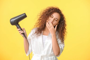 Renkli fön makinesi olan güzel, uykulu bir Afro-Amerikalı kadın.