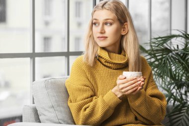 Güzel genç bayan evde çay içiyor.