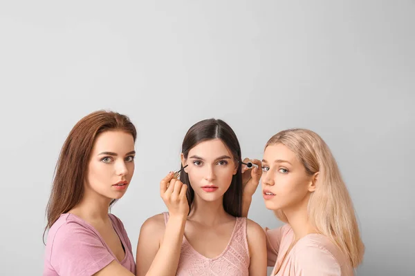 Jovens Mulheres Bonitas Aplicando Maquiagem Fundo Claro — Fotografia de Stock