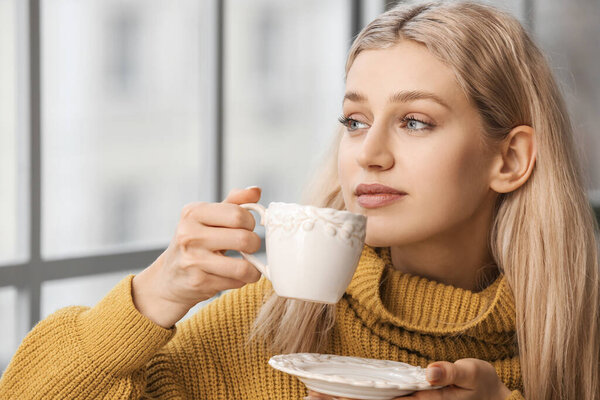 Beautiful young woman drinking tea at home