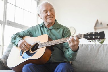 Evde gitar çalan yaşlı bir adam.