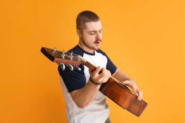 Arka planda gitar çalan genç bir erkek şarkıcı.