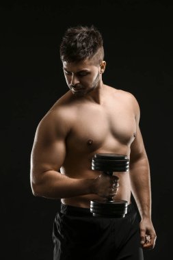 Koyu arka plan üzerinde halter ile sportif genç adam