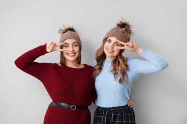 Hafif arka planda kalın kazaklı genç kadınlar.