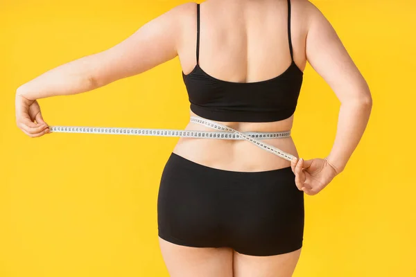 色の背景に測定テープを持つ太りすぎの女性 減量の概念 — ストック写真