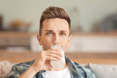 Genç adam evde süt içiyor.