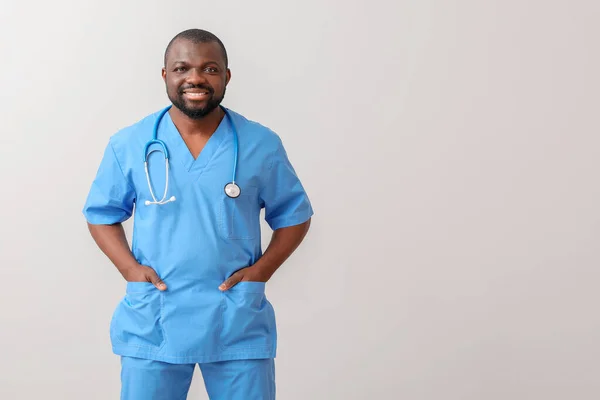 African-American doctor on light background