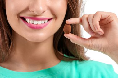 Beyaz arka planda çikolata şekerli güzel genç kadın, yakın plan.