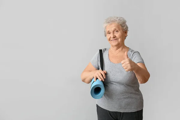 Elinde Yoga Minderi Olan Yaşlı Bir Kadın Arka Planda Baş — Stok fotoğraf