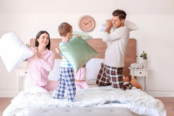 Happy family fighting on pillows in bedroom at home