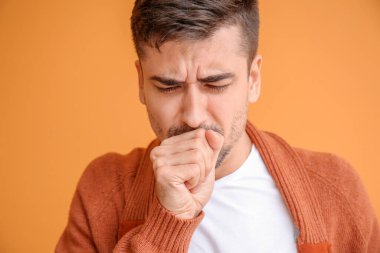 Renkli arka planda öksüren genç adam