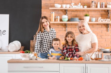 Büyük aile mutfakta birlikte yemek pişiriyor.