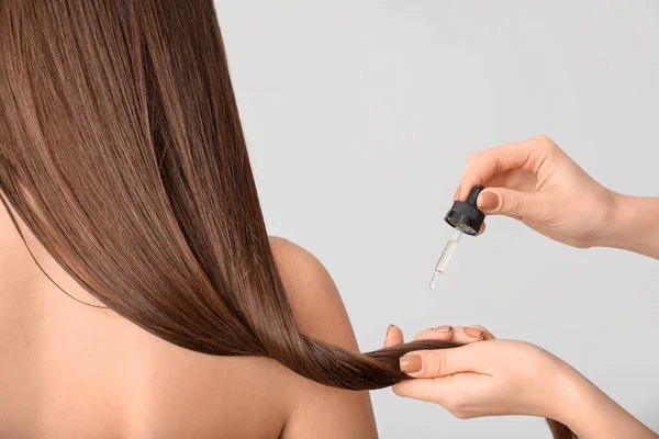 Aplicação Cosméticos Cabelo Mulher Contra Fundo Cinza — Fotografia de Stock