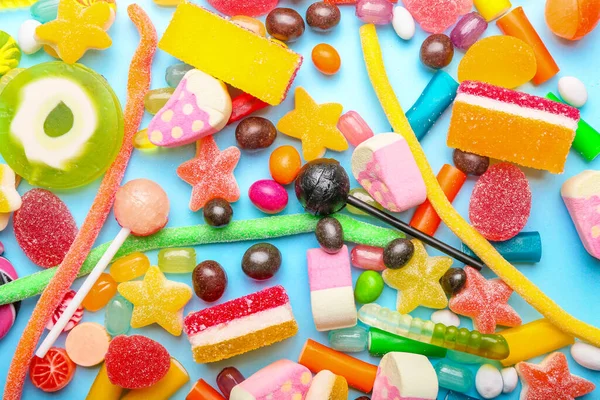 Assortment of sweet candies on color background