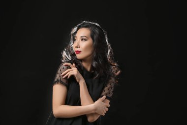 Siyah arka planda güzel saçları olan genç Asyalı kadın.