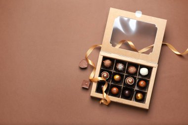 Renkli arka planda lezzetli çikolata şekerleriyle dolu bir kutu