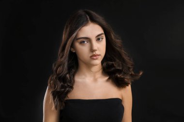 Siyah arka planda güzel kıvırcık saçlı genç bir kadın.