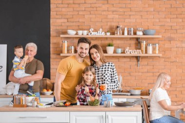 Büyük aile mutfakta birlikte yemek pişiriyor.