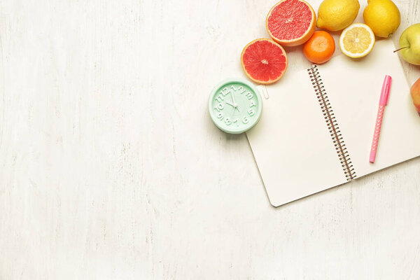 Ноутбук со свежими фруктами и часами на столе
