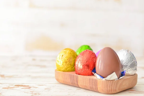 Box with sweet chocolate eggs on wooden background