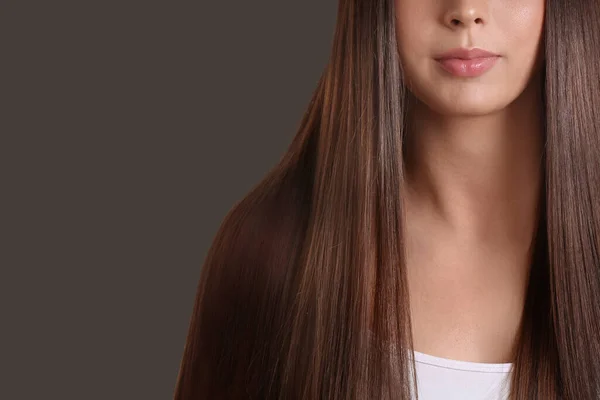 Young woman with beautiful straight hair on grey background