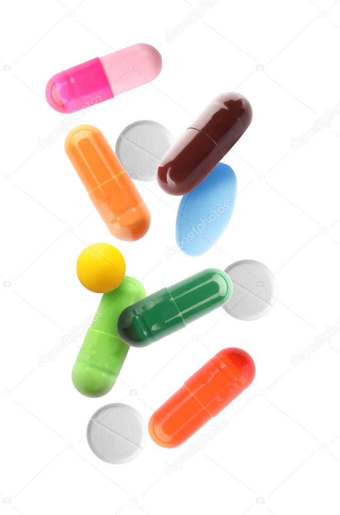 Different falling pills on white background