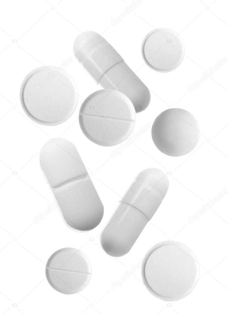 Different falling pills on white background