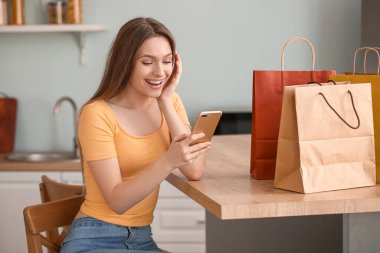 Cep telefonu ve alışveriş çantaları olan genç bir kadın.