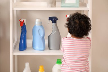 Evde yıkanan sıvılarla oynayan küçük bir Afro-Amerikalı bebek. Çocuk tehlikede.