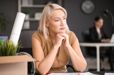 Ofisinde kişisel eşyaları olan üzgün, olgun bir kadın kovuldu.