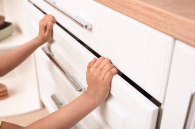 Küçük Afro-Amerikalı çocuk mutfakta çekmeceyle oynuyor. Çocuk tehlikede.