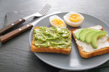 Masada lezzetli avokado sandviçli tabak.