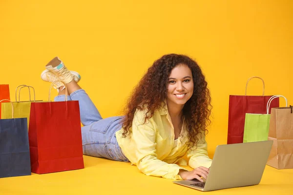 Jonge Vrouw Met Laptop Boodschappentassen Kleur Achtergrond — Stockfoto