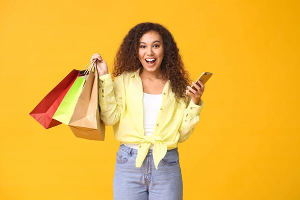 Happy Vrouw Met Mobiele Telefoon Boodschappentassen Kleur Achtergrond — Stockfoto