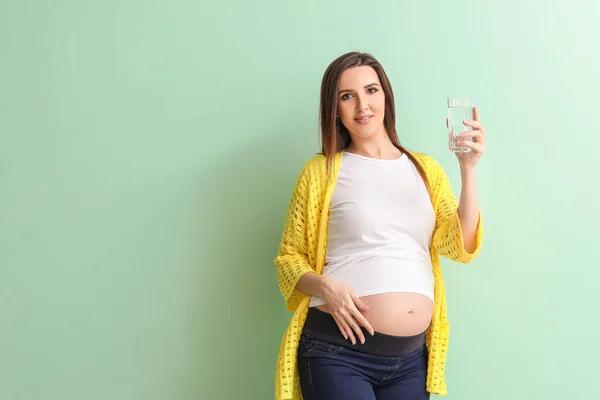 Schöne Schwangere Frau Mit Einem Glas Wasser Auf Farbigem Hintergrund — Stockfoto