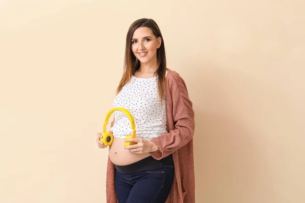 Hermosa Mujer Embarazada Poniendo Auriculares Vientre Contra Fondo Color —  Fotos de Stock