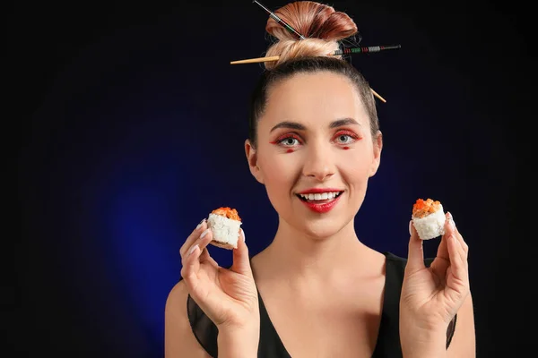 暗い背景でおいしい寿司を持つ美しい女性 — ストック写真