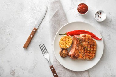 Beyaz arka planda pişmiş domuz eti ve sebzeli tabak.