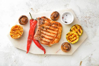 Beyaz arka planda pişmiş domuz eti ve sebzeli pano.