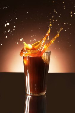 Koyu arkaplanda bardakta kahve sıçraması.