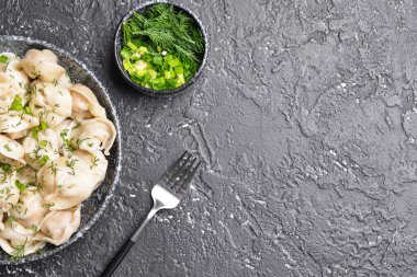 Lezzetli hamur tatlısı ve koyu arkaplanda otlarla dolu bir kase.