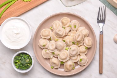 Lezzetli hamur tatlısı, yeşil soğan ve soslu bir tabak.