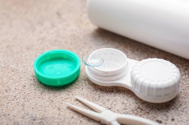 Gri arkaplanda kontakt lens, çözüm ve cımbız