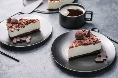 Lezzetli çikolatalı cheesecake tabakları ve koyu arkaplanda bir fincan kahve.