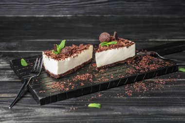 Koyu ahşap arka planda lezzetli çikolatalı cheesecake parçaları olan tahta.