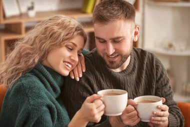 Mutlu genç çift evde sıcak çikolata içiyor.