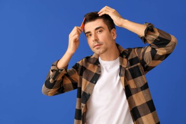 Renkli arka planda saç tarayan yakışıklı genç adam