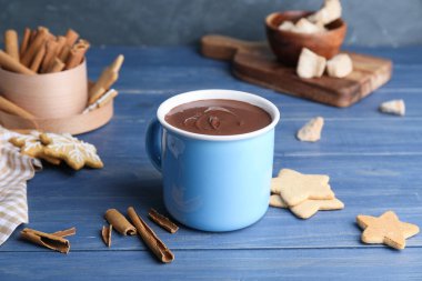 Masada bir fincan sıcak çikolata, tarçın ve kurabiye.